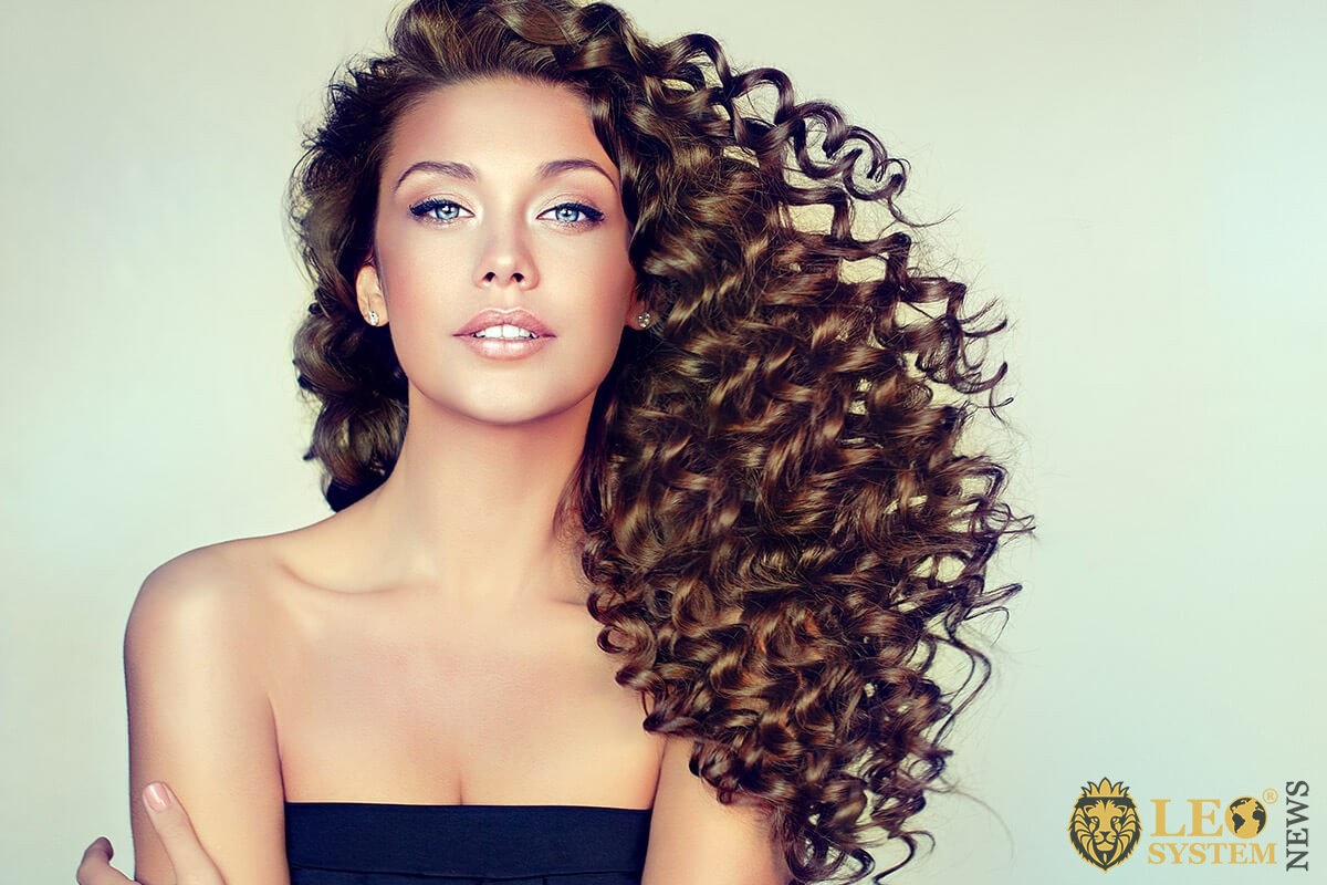 Beautiful woman shows a well-groomed and curly locks of hair