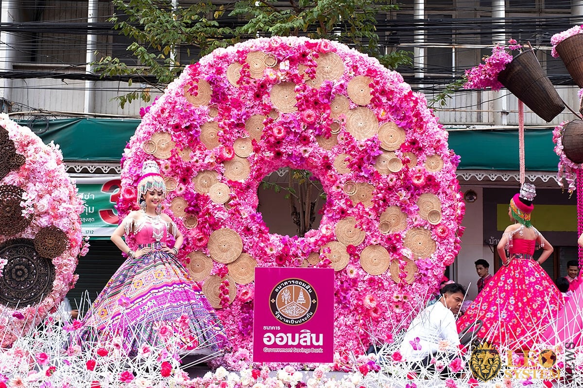 Young women dressed in colorful clothes standing in a colorful flower float at the Flower Festival Parade, Chiang Mai