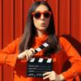 Image of disciplined woman with clapperboard in hands