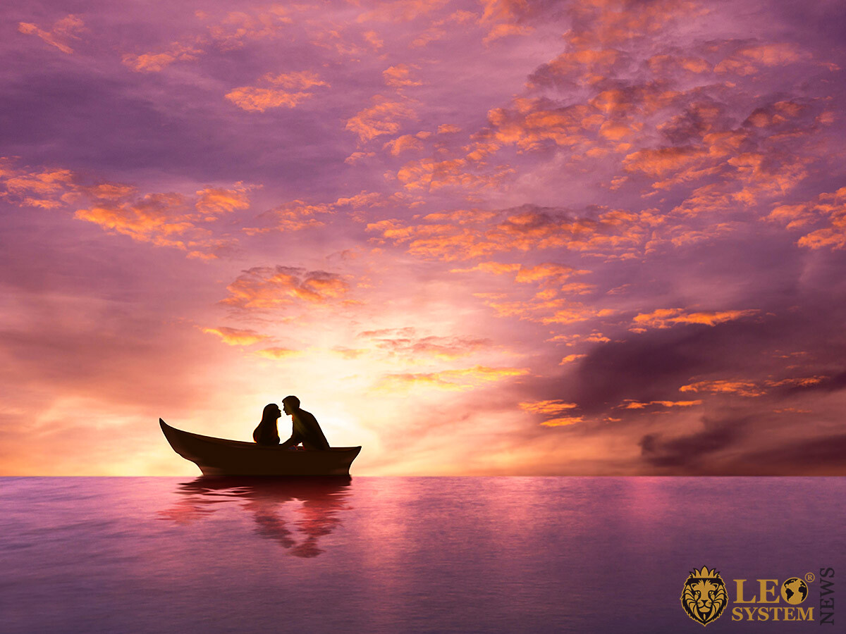 Lovers man and woman sail on a boat at the time of sunset