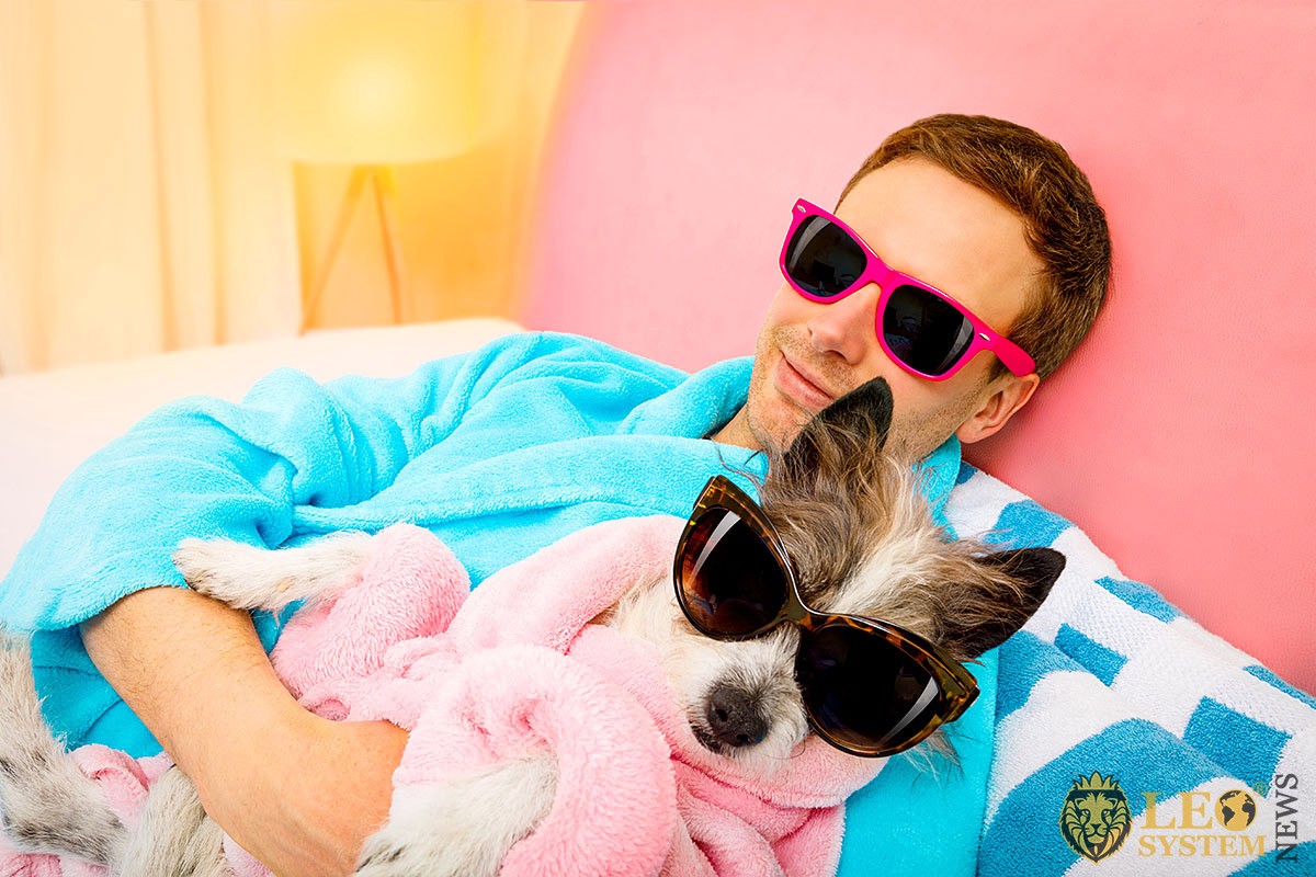 Positive young guy with a dog in glasses